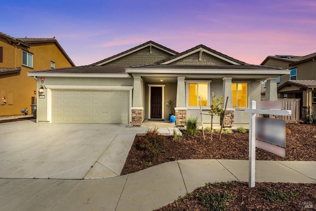 craftsman house featuring driveway, covered porch, stucco siding, stone siding, and a garage