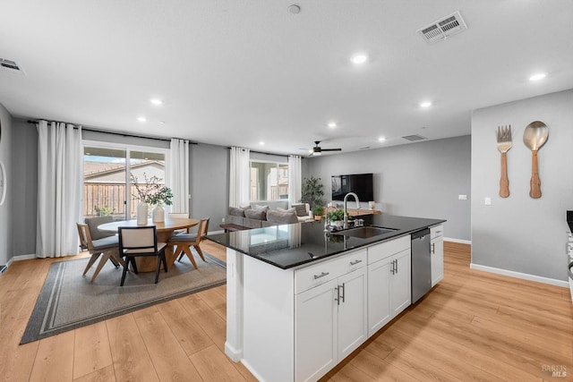 kitchen featuring visible vents, light wood finished floors, a sink, white cabinets, and stainless steel dishwasher