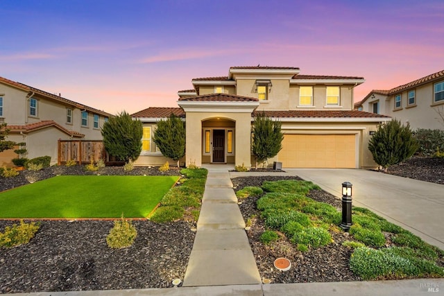 view of front of house featuring a tile roof, stucco siding, an attached garage, fence, and driveway