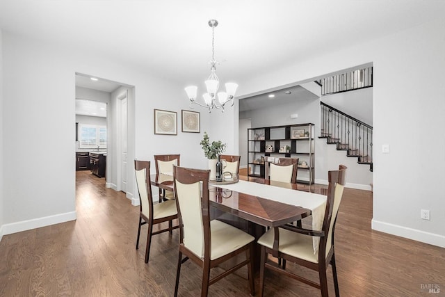 dining space with stairs, a chandelier, baseboards, and wood finished floors