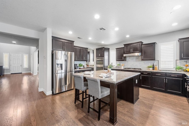 kitchen featuring dark wood finished floors, visible vents, appliances with stainless steel finishes, a kitchen island, and under cabinet range hood