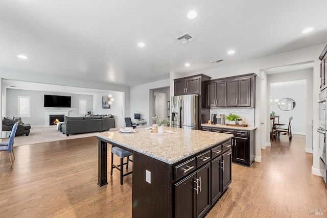 kitchen with a breakfast bar, a lit fireplace, visible vents, and stainless steel appliances