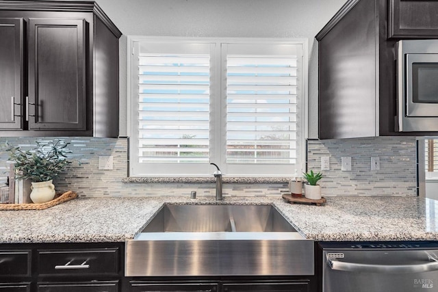 kitchen featuring light stone counters, appliances with stainless steel finishes, backsplash, and a sink