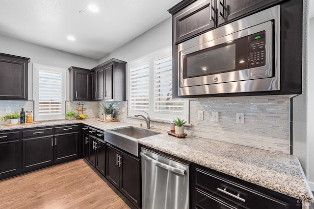 kitchen featuring stainless steel appliances, light wood-style flooring, a sink, and a wealth of natural light