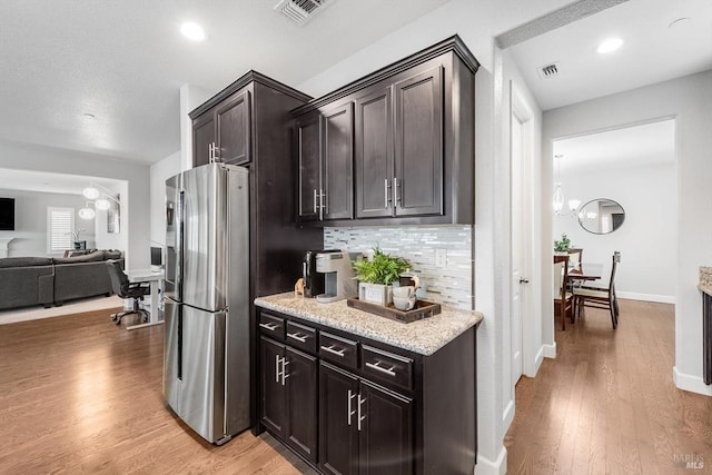 kitchen featuring light wood finished floors, visible vents, stainless steel refrigerator with ice dispenser, and backsplash