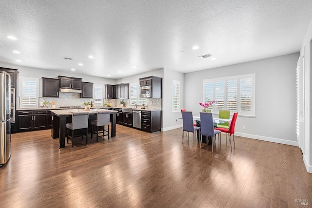 dining area featuring a healthy amount of sunlight, dark wood finished floors, visible vents, and baseboards