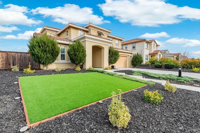 mediterranean / spanish-style house featuring a garage, fence, concrete driveway, stucco siding, and a front lawn