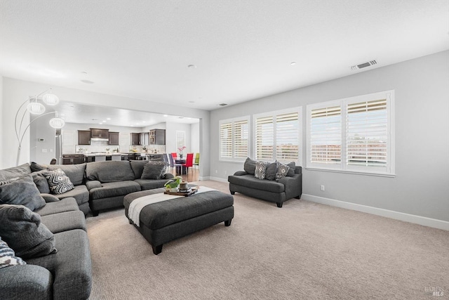 living room featuring light colored carpet, visible vents, and baseboards