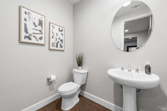 half bath with toilet, baseboards, and wood finished floors