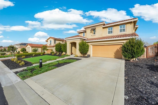 mediterranean / spanish home with a garage, a tile roof, driveway, stucco siding, and a front lawn