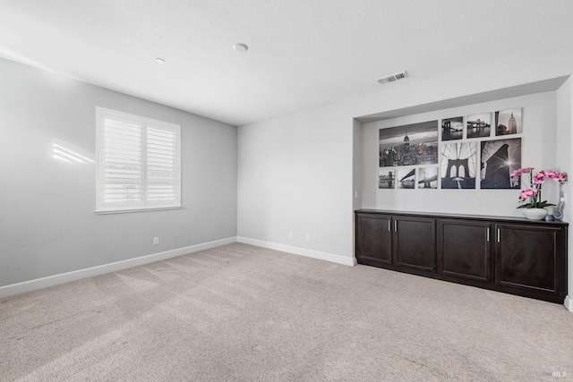 carpeted empty room featuring visible vents and baseboards