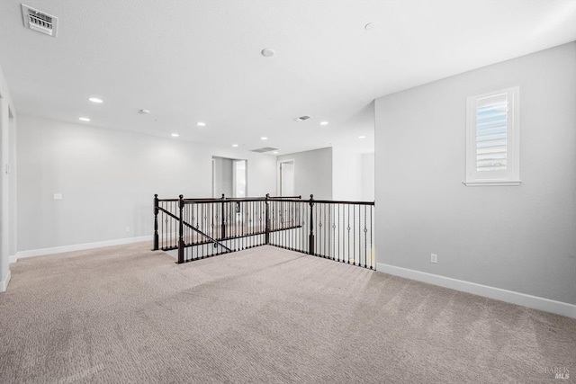 spare room featuring recessed lighting, carpet flooring, visible vents, and baseboards