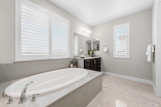 full bathroom featuring a wealth of natural light, a garden tub, vanity, and baseboards