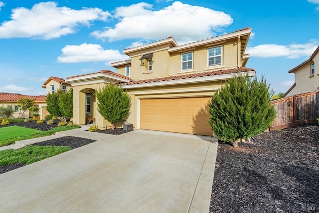 mediterranean / spanish house featuring driveway, a garage, a tiled roof, fence, and stucco siding