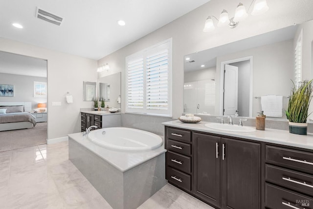 ensuite bathroom featuring a healthy amount of sunlight, a sink, visible vents, and a garden tub