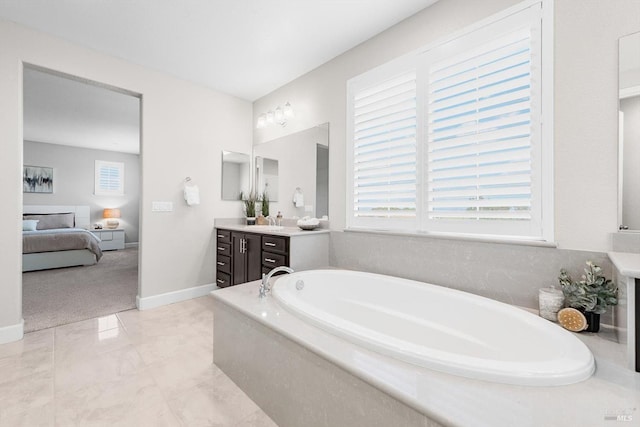 ensuite bathroom with baseboards, connected bathroom, a garden tub, marble finish floor, and vanity