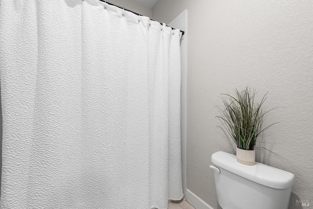 full bath featuring a textured wall and toilet