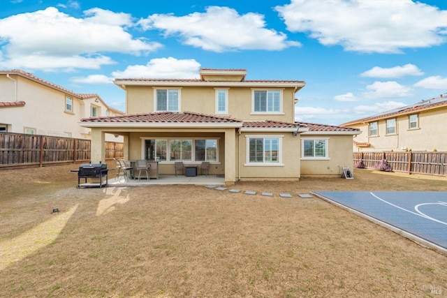 back of property with a yard, a tile roof, a fenced backyard, and stucco siding