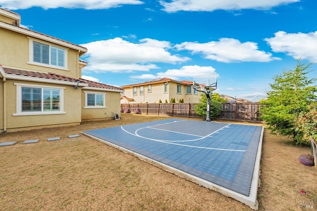 view of sport court with fence private yard, basketball court, and a lawn