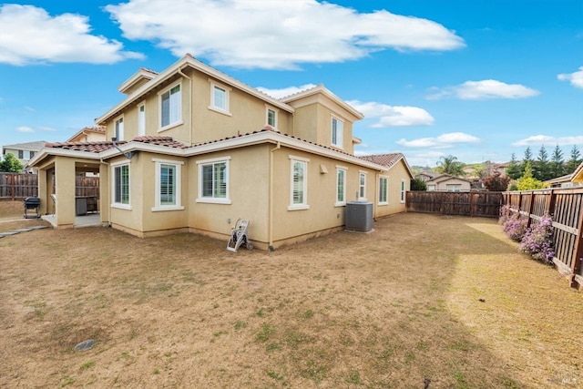 back of house featuring a fenced backyard, a tile roof, a lawn, and stucco siding