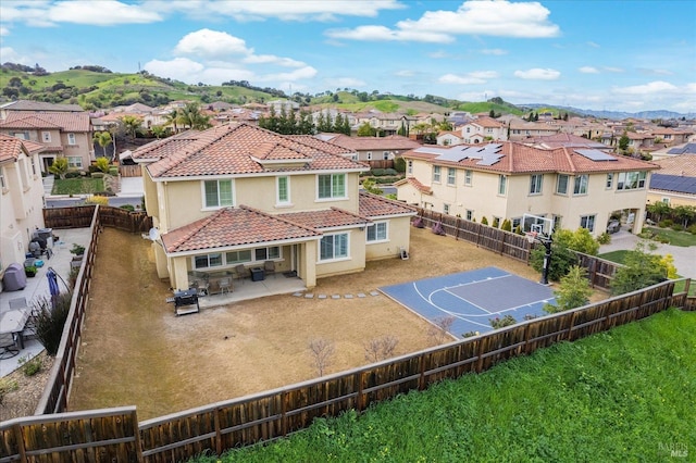 back of house featuring a residential view, a tile roof, a fenced backyard, and stucco siding