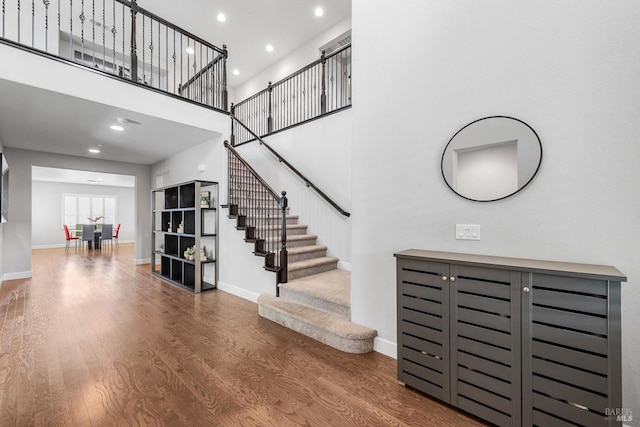 foyer entrance featuring a high ceiling, stairway, baseboards, and wood finished floors