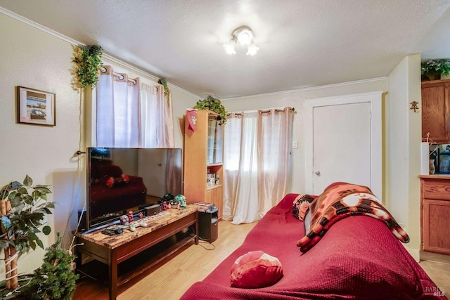 bedroom featuring a textured ceiling, ornamental molding, and light wood-style flooring