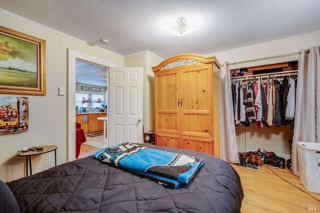 bedroom with ornamental molding, a closet, a textured ceiling, and wood finished floors