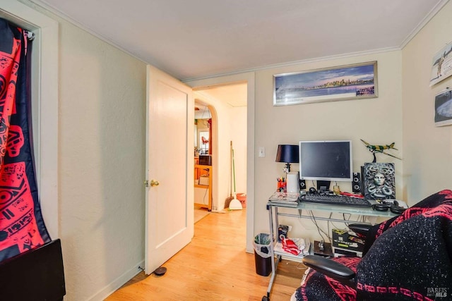 home office featuring baseboards, arched walkways, wood finished floors, and ornamental molding