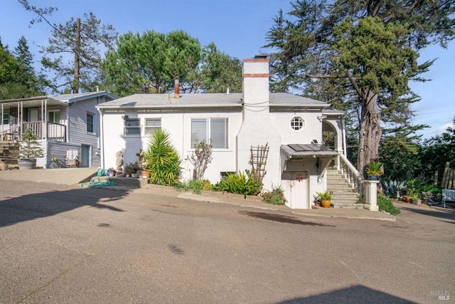 view of front of home with a chimney and stucco siding