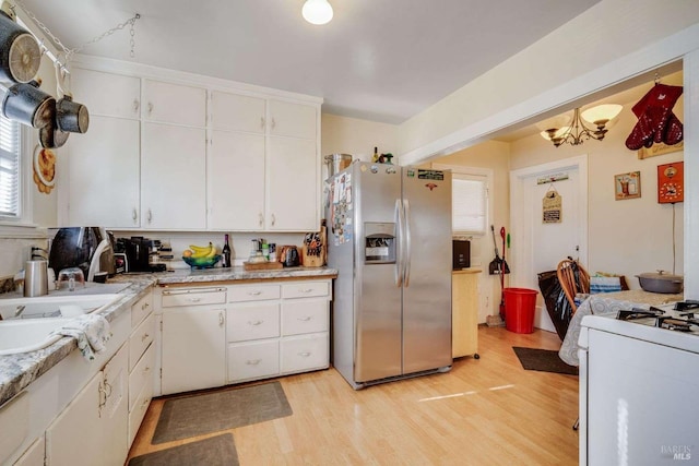 kitchen with white appliances, white cabinets, light countertops, light wood-type flooring, and a sink