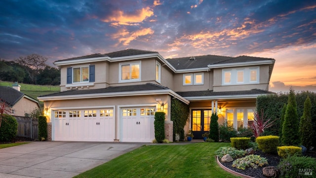 view of front of home with fence, concrete driveway, stucco siding, a yard, and an attached garage