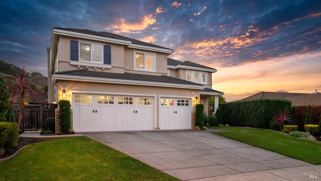 view of front of home featuring a garage, a yard, driveway, and stucco siding