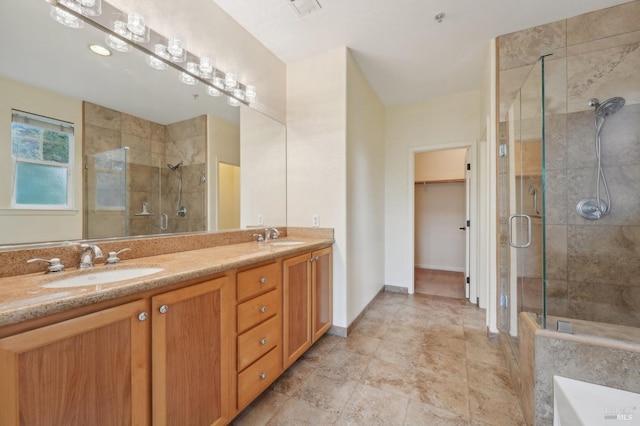 bathroom with a stall shower, a sink, a spacious closet, and double vanity