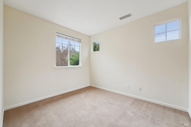 carpeted spare room with visible vents and baseboards