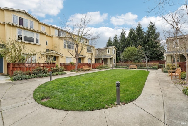 view of property's community featuring a residential view, fence, and a lawn