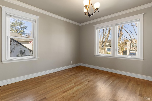 spare room featuring a healthy amount of sunlight, a notable chandelier, and baseboards