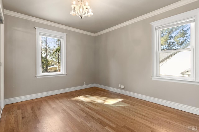 spare room featuring an inviting chandelier, baseboards, crown molding, and wood finished floors