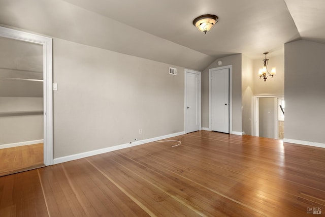 interior space with baseboards, visible vents, vaulted ceiling, and hardwood / wood-style floors