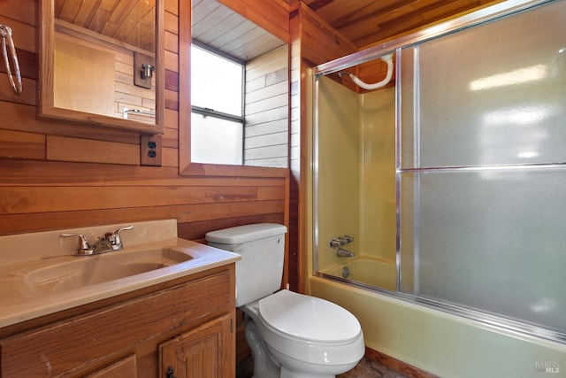 bathroom featuring enclosed tub / shower combo, wood walls, vanity, and toilet