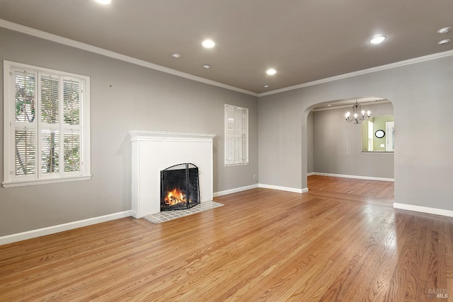 unfurnished living room with arched walkways, a fireplace with flush hearth, light wood-style flooring, and baseboards