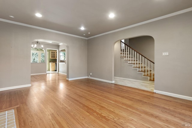 unfurnished living room with arched walkways, recessed lighting, wood finished floors, baseboards, and stairs