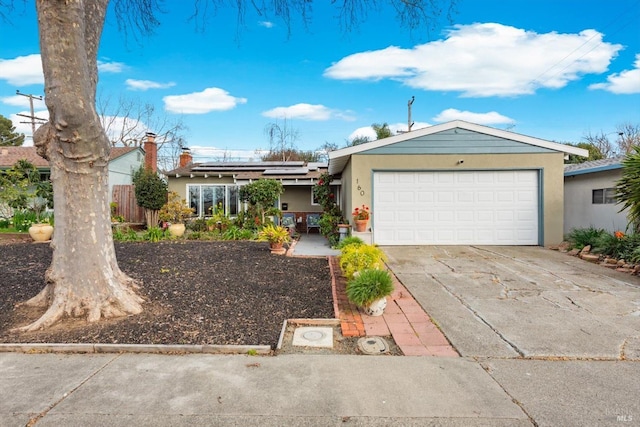 view of front facade featuring a garage, concrete driveway, stucco siding, and roof mounted solar panels