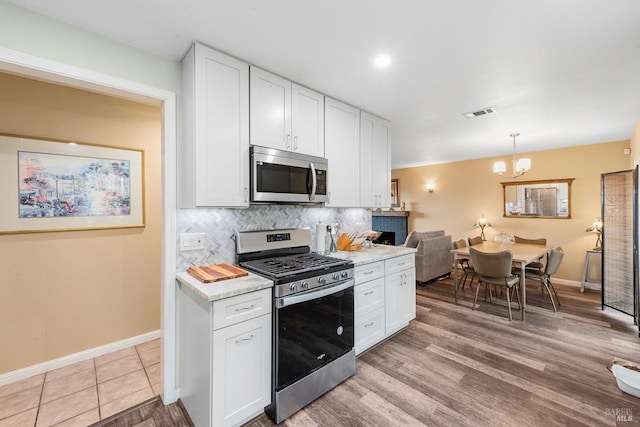 kitchen featuring white cabinets, appliances with stainless steel finishes, and decorative backsplash