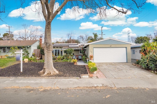 view of front of property with an attached garage, solar panels, concrete driveway, and stucco siding