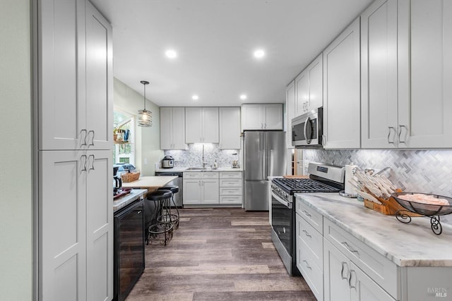 kitchen with wine cooler, stainless steel appliances, dark wood-style flooring, hanging light fixtures, and backsplash