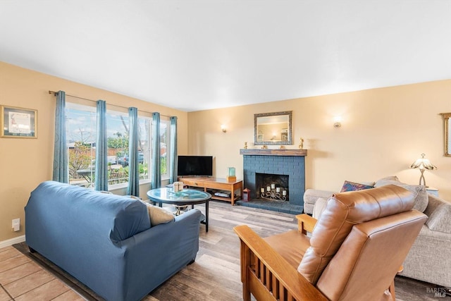 living room featuring a brick fireplace, baseboards, and wood finished floors