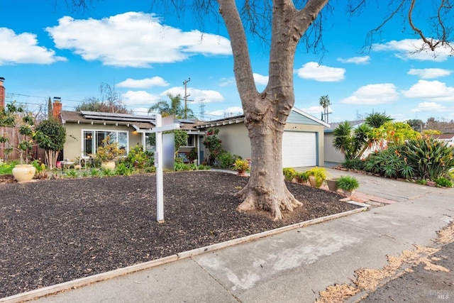 view of front facade featuring solar panels, fence, an attached garage, and stucco siding