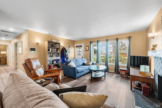 living room with baseboards, a fireplace, visible vents, and wood finished floors