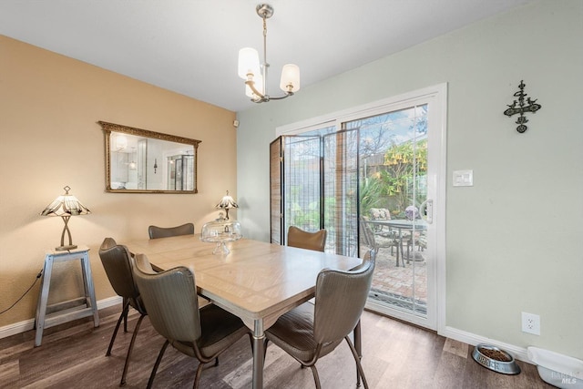 dining space featuring baseboards, wood finished floors, and an inviting chandelier